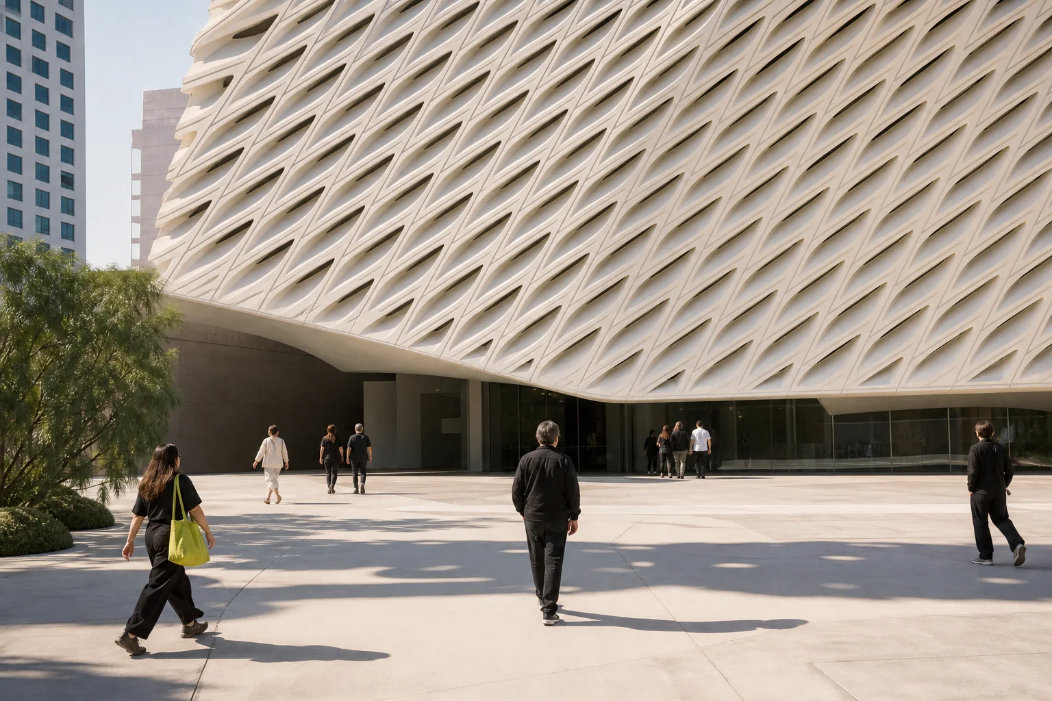 Visitors cross a sunny plaza beneath a white honeycomb museum facade in downtown Los Angeles.